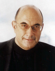 Bald man wearing glasses and black suit.