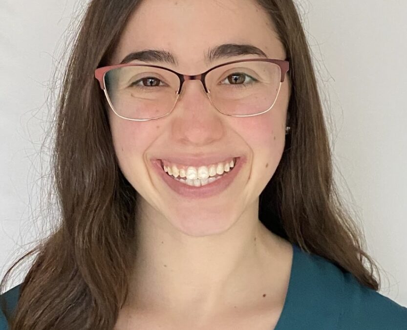 Smiling woman with glasses and brown hair.