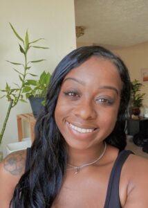 Smiling person with plants in the background.