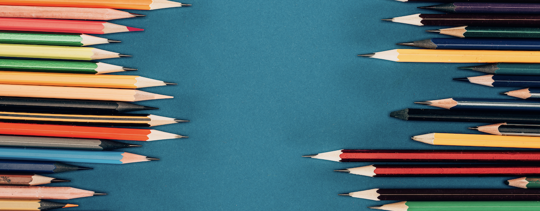 Colored pencils arranged on blue background.