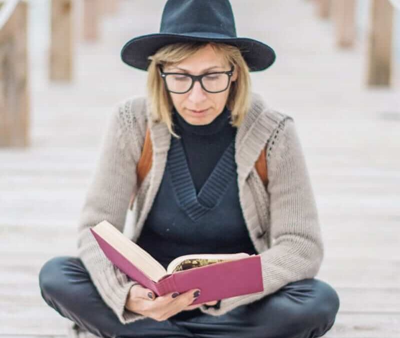Woman reading book on wooden pier.