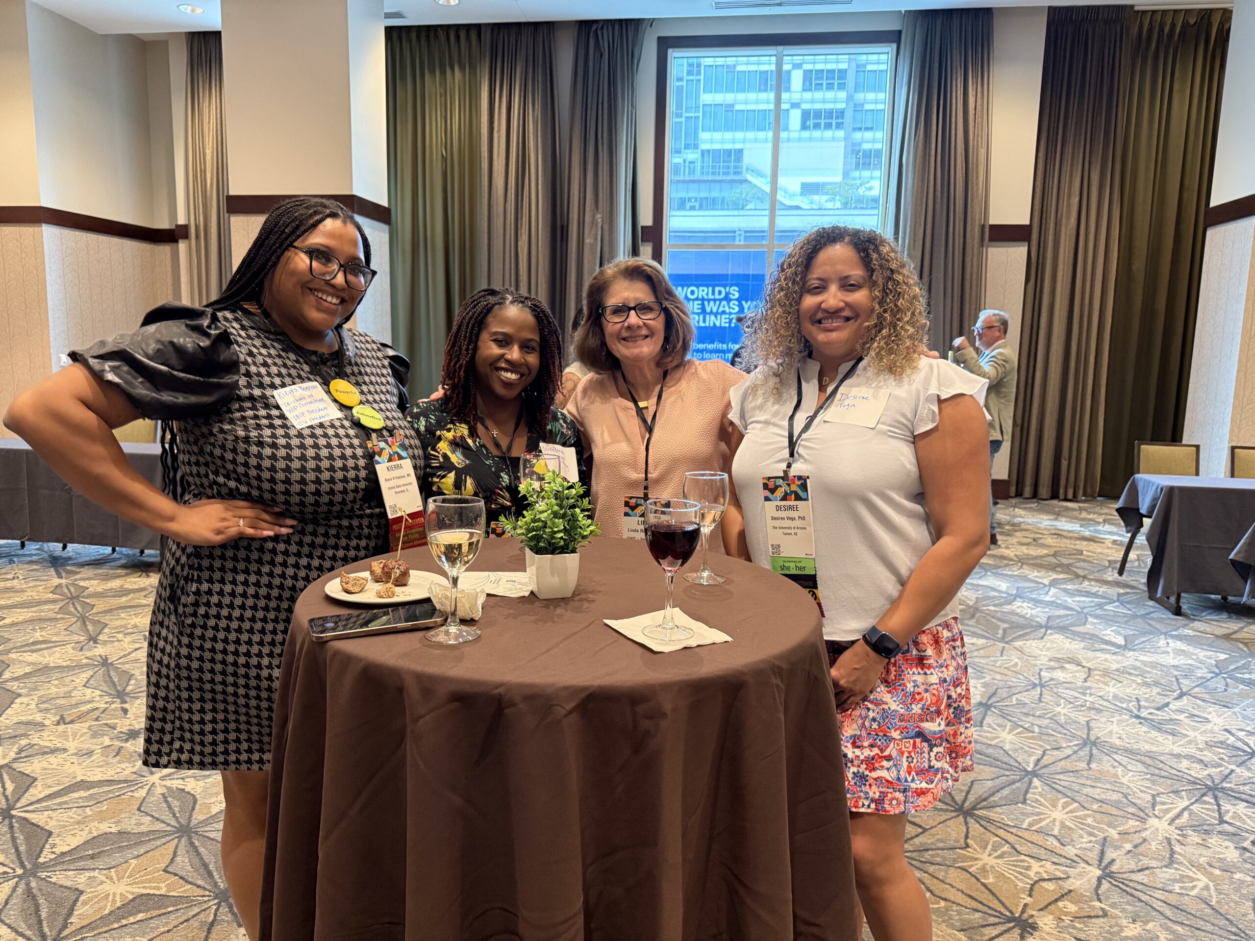 Four women smiling at a conference event.