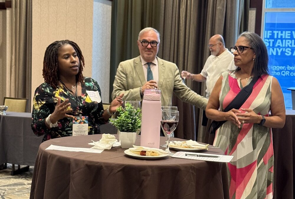 People conversing around a table at event.